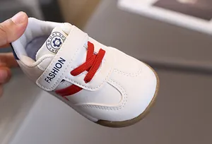 Detail of white leather toddler sneakers with red laces and non-slip rubber soles