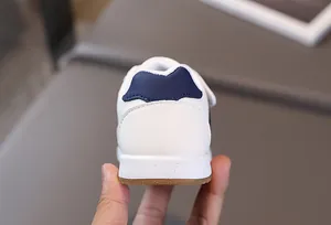 Detailed view of white toddler sneakers featuring navy heel accents and anti-slip rubber soles