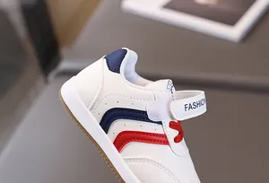 Detail of white kids sneakers featuring red and blue stripes and non-slip gum sole