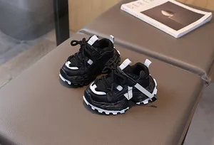 Detalle de zapatillas negras para niños con suela gruesa ondulada sobre superficie