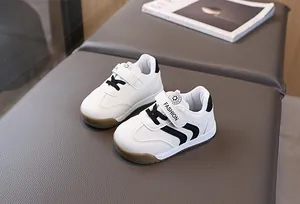 Detail view of toddler white sneakers featuring velcro straps and durable brown rubber soles