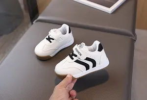 Detail of toddler sneakers with white leather, black stripes and non-slip rubber sole