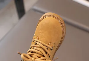 Close-up of yellow leather kids boot with stitching detail and textured laces