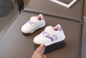 Detail view of white toddler sneakers with purple velcro strap and durable rubber sole