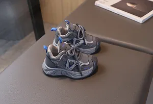 Close-up of children's grey mesh sneakers on leather bench with blue pull tabs