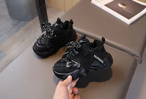 Close-up of black children sneakers featuring mesh leather textures and thick soles