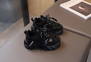 Detail of kids black chunky sneakers with mesh upper and velcro strap on gray leather