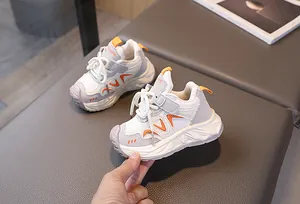 Detailed side view of kids sneakers featuring orange accents and velcro straps