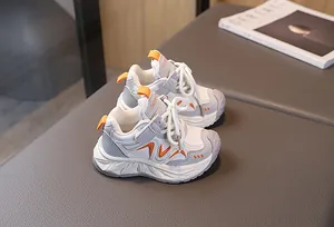 Detail view of children's sneakers in white grey and orange with velcro strap and laces
