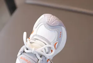 Detail of kids sporty sneaker featuring orange FASHION text and reinforced toe cap