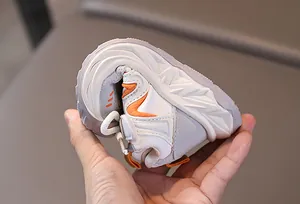 Close-up of highly flexible and soft rubber sole of kids sports shoes in orange and white