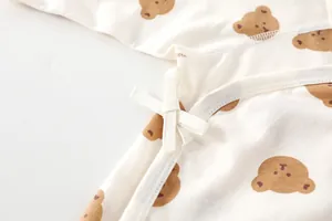 Detail of newborn cotton bodysuit showing brown bear print and side tie closure design