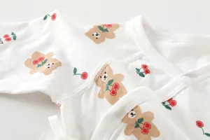 Close-up of baby bodysuit neckline with cute bear and cherry prints on cotton fabric