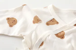 Detailed view of baby bodysuit's soft cotton fabric with cute brown bear patterns
