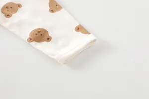Detailed macro view of soft cotton baby romper cuff with brown bear print and stitching