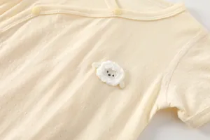 Gros plan du body bébé beige avec tissu en maille respirant et écusson d'agneau