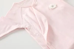 Detail of baby pink bamboo fiber romper featuring a cute sheep patch and snap buttons