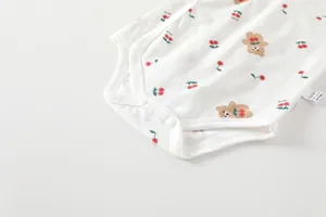 Close-up of cotton baby bodysuit with cherry and bear print and metal snap buttons