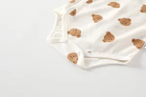 Detailed view of baby bodysuit snap fasteners and cute cartoon bear print on soft cotton