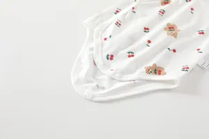 Close-up of baby cotton bodysuit featuring cherry and bear prints with snap buttons