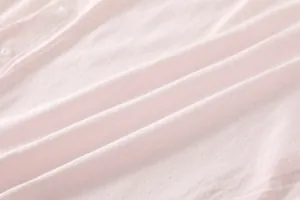 Detailed macro view of soft pink bamboo fiber knit fabric with delicate pointelle patterns