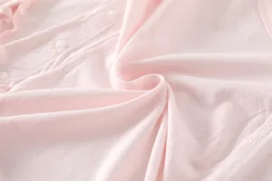Macro detail of breathable pink bamboo fiber baby bodysuit with three white buttons