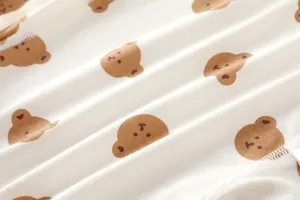 Detailed macro view of soft cream cotton knit fabric with brown cartoon bear pattern