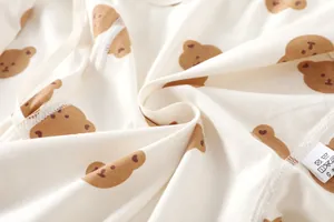 Detailed macro shot of premium soft cotton fabric with cute brown bear patterns and wash label