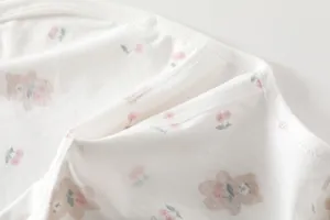Close-up of soft cotton newborn bodysuit fabric with cute brown bear and cherry print