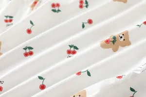 Detail of soft cotton baby romper fabric with cherry and bear print and size label