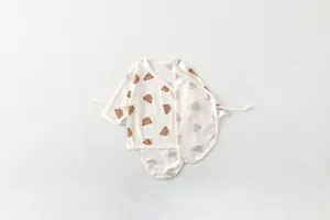 Detail of newborn baby bodysuit featuring side ties and cute brown bear patterns