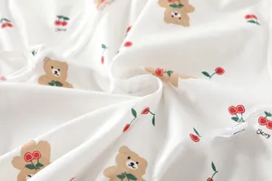 Macro detail of soft cotton baby bodysuit fabric with bear and cherry prints
