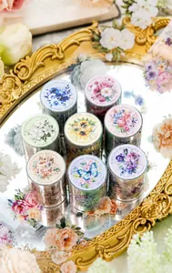 Detalle de siete rollos de cinta washi de flores y mariposas en bandeja retro