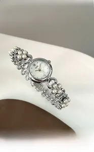 Detailed macro view of silver quartz watch with pearl chain strap and pearl dial
