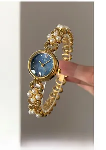 Close-up of gold quartz watch with pearl chain strap and blue mother of pearl dial