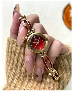Close-up of GEDI ladies gold metal watch with red dial and enamel bracelet accents