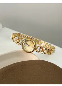 Detailed macro view of GEDI gold watch dial with elegant pearl chain bracelet