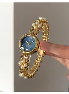 Detailed shot of gold watch with blue pearl dial and elegant pearl chain bracelet strap