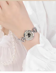 Detail einer silbernen Herz-Armbanduhr mit polierten Gliedern am Handgelenk einer Frau