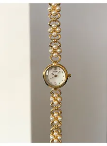 Macro detail of GEDI watch with gold floral chain links and white pearl inlays
