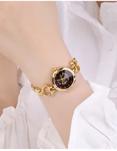 Nahaufnahme der eleganten goldfarbenen Uhr mit rotem Zifferblatt und Herz-Kettengliedern
