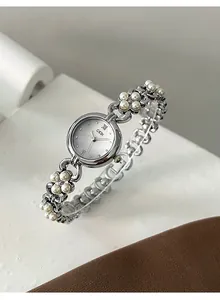 Detailed macro view of silver quartz watch with white pearls and চার petal flower chain strap