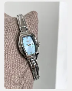 Detailopname van een zilverkleurig tonneau-horloge met een lichtblauwe wijzerplaat