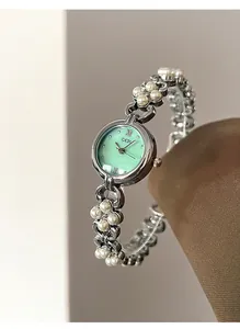 Detailed shot of mint green dial watch with cluster pearl band on display stand