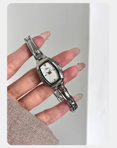 Macro-opname van zilveren tonneau-horloge met gepolijste armband aan damespols