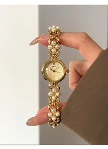 Detail of elegant gold-tone watch featuring a unique floral pearl bracelet strap