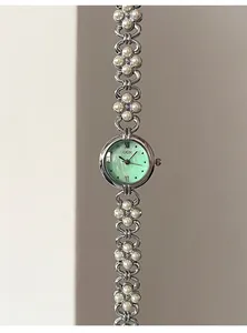 Detail of mint green dial quartz watch with pearl flower chain strap and silver metal