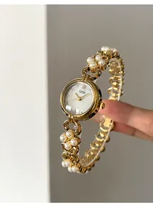 Close-up of elegant pearl chain watch band with gold metal links and white dial face