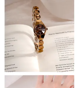 Détail d'une montre à quartz or rose avec bracelet à facettes sur un fond de livre ouvert