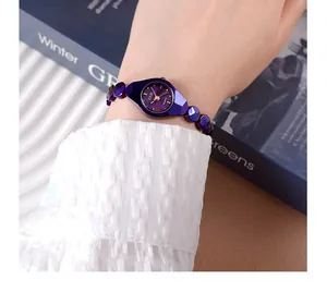 Détails macro d'une montre bijou violette avec aiguilles dorées et bracelet perlé